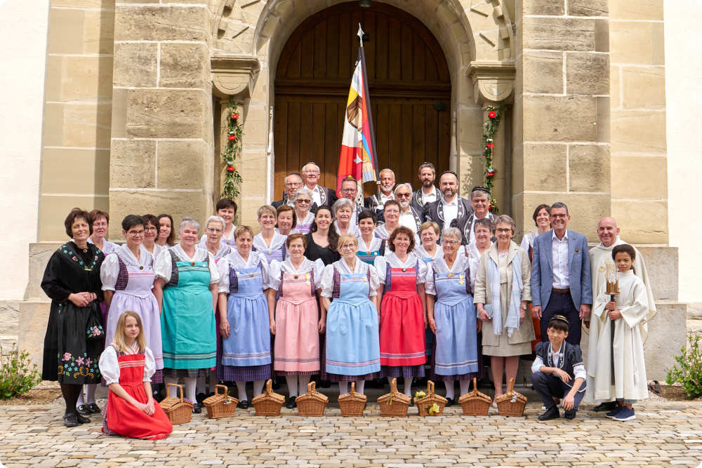 Photo de groupe du chœur mixte de rossens, en costume, devant l'église de Rossens On voit le chœur mixte de Rossens en costume d'époque, posant devant l'église de Rossens à l'occasion de la célébration de la nouvelle bannière en 2023
